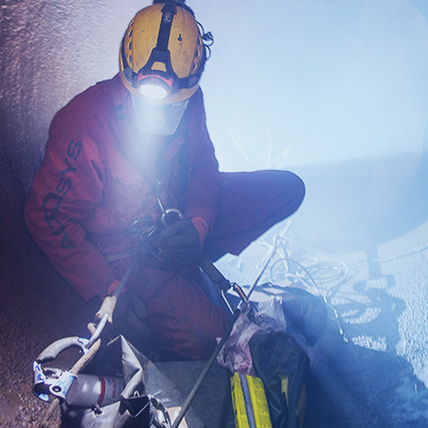 Operario dentro de una gran tubería con línea de vida y equipo de respiración de escape