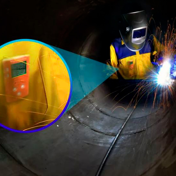 Operario realizando trabajos de soldadura en una tubería, con detector de gases y explosividad.