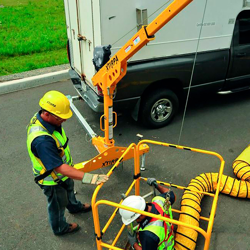 Brazo de rescate anclado a furgoneta, usando esta como contrapeso y operario entrando en la alcantarilla, protegido por una barandilla.